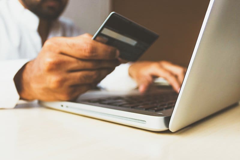 A man holding a credit card inputting the number into a computer