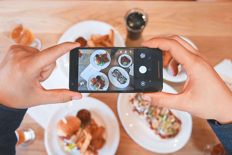 A person taking a photo of a table of food.