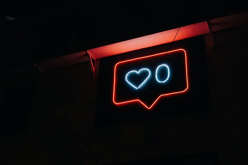 A neon sign with a blue heart and a 0 for 0 likes